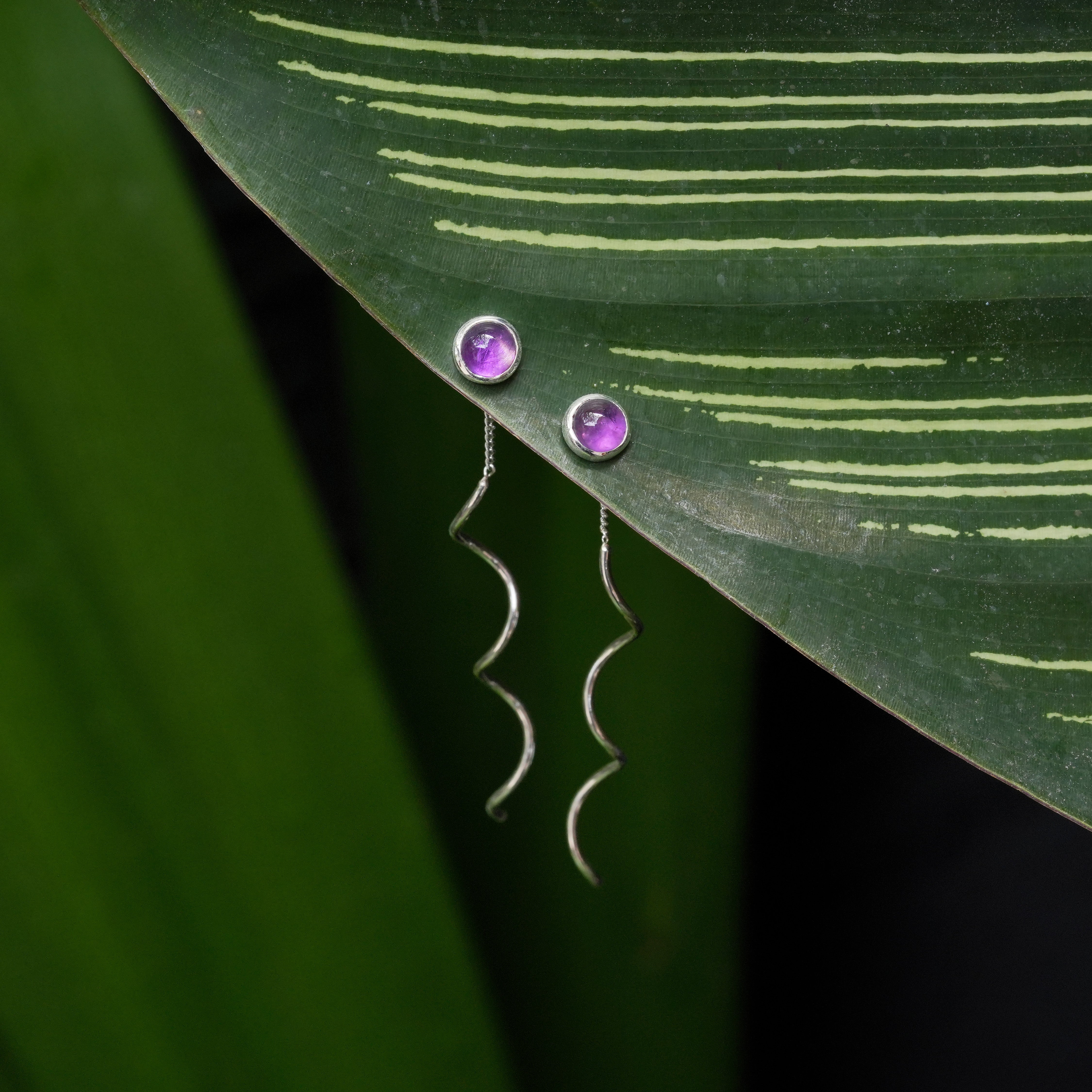Front view of a round Amethyst stud earrings with flowing curled sterling silver wire drops shown in a close‑up product view.