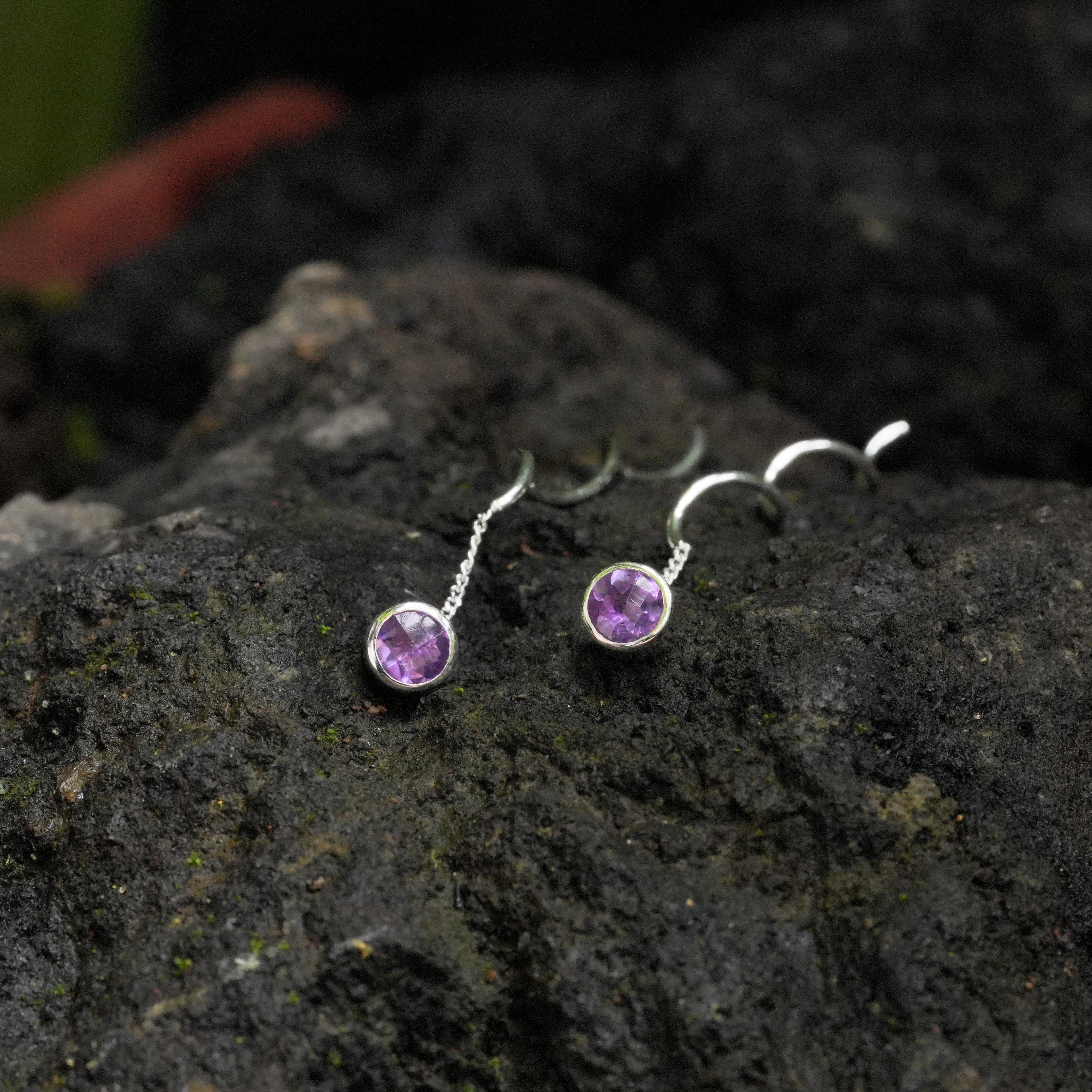 Faceted amethyst stud earrings with flowing curled sterling silver wire shown in a close‑up product view displaying the clear purple faceted stones.