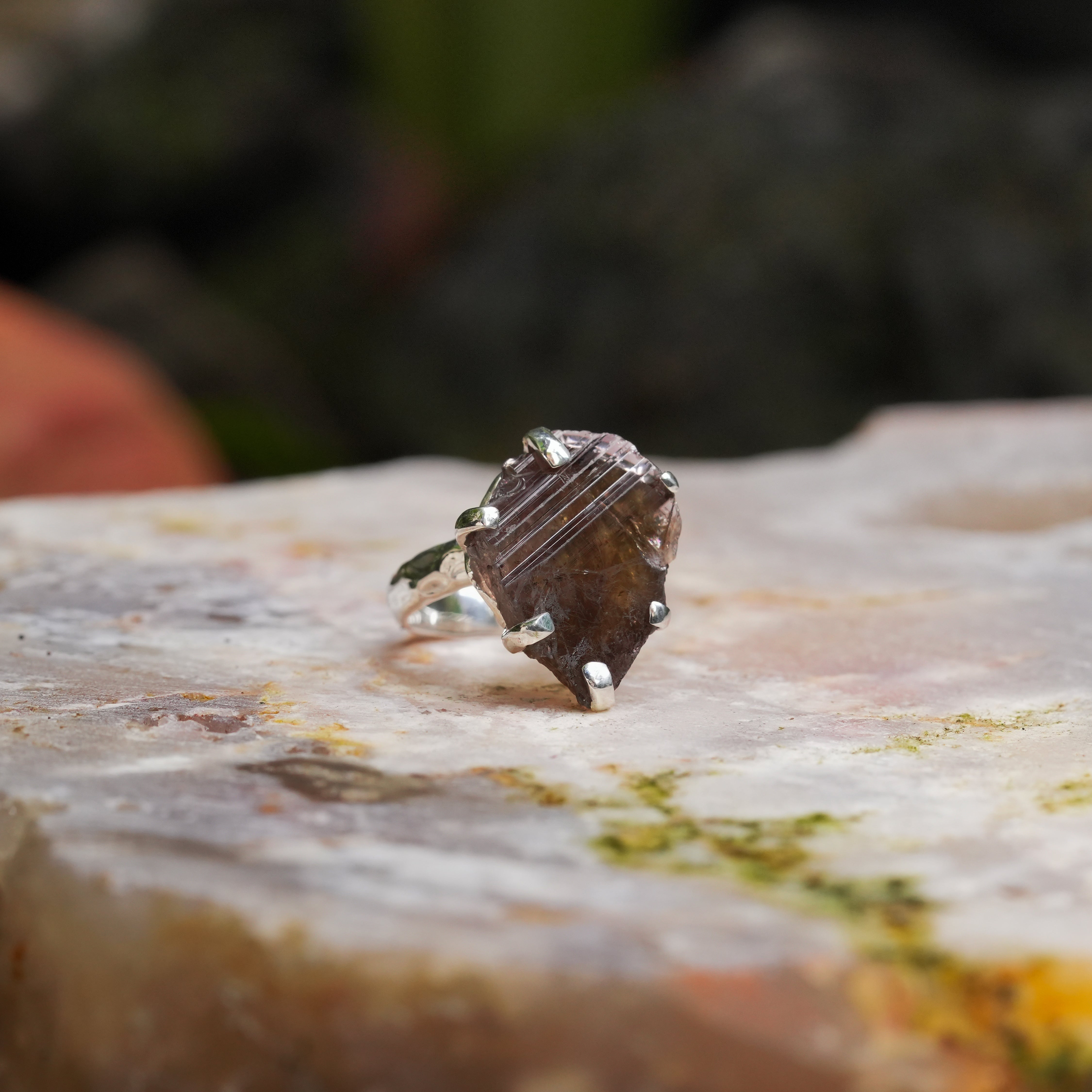 Alternate angled view of an Axinite prong‑set ring showing the free‑form crystal and the hammered band