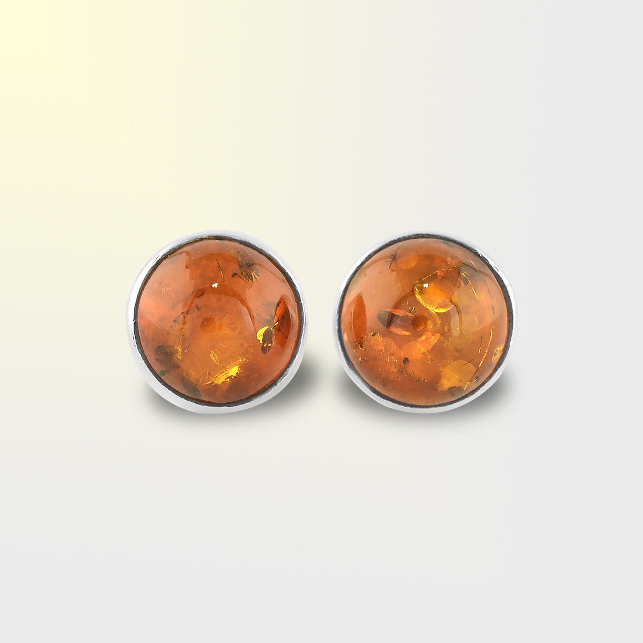 Alternate artistic front view of silver stud earrings featuring round Baltic Amber gemstones with natural inclusions.