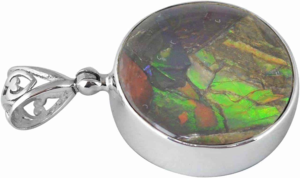 Front‑view angled image of a round pendant featuring multicolored Ammolite set in a polished silver frame with a filigree bail, showing the stone pattern and the thickness of the silver bezel.