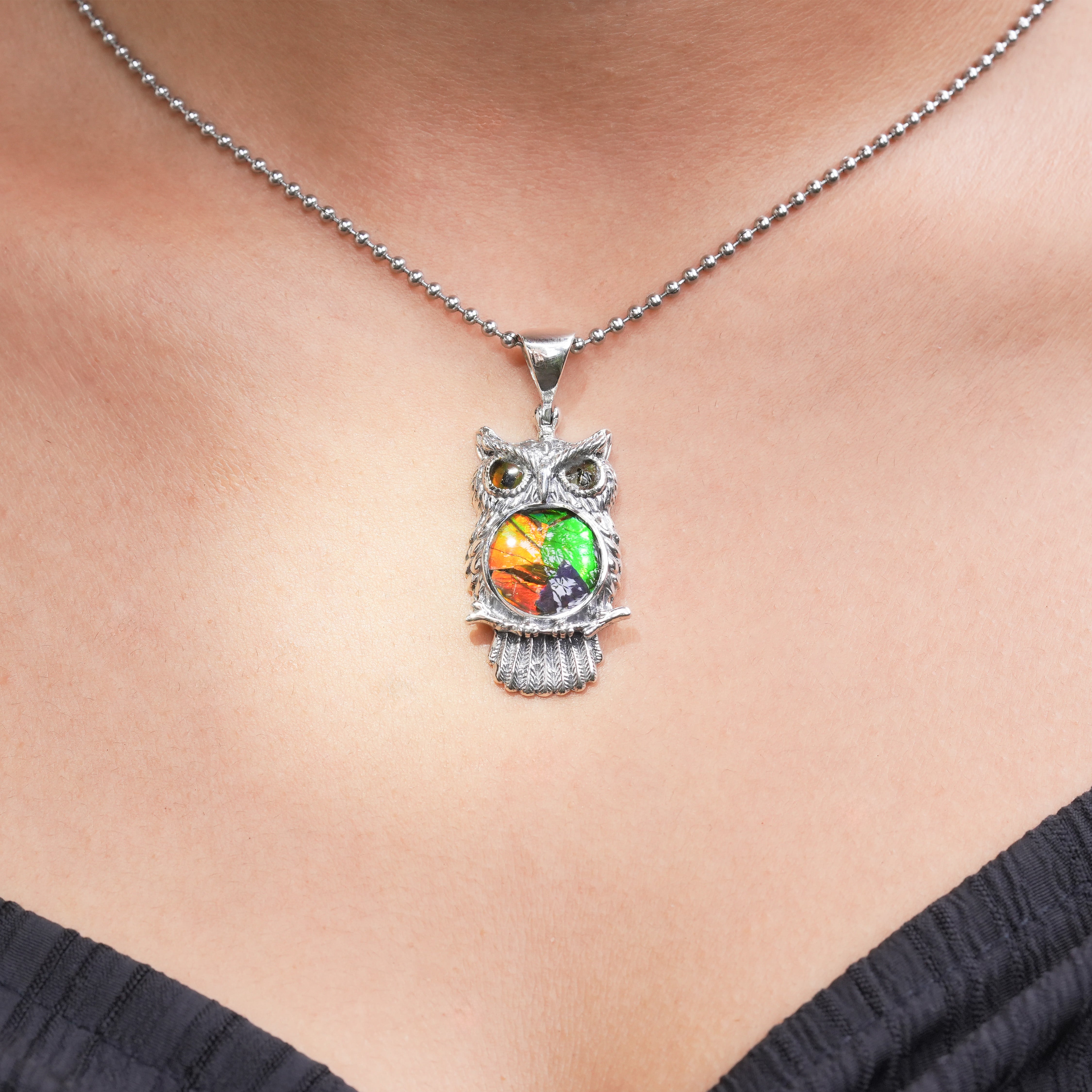 Owl pendant necklace with a multicolor ammolite inlay shown worn to indicate scale.