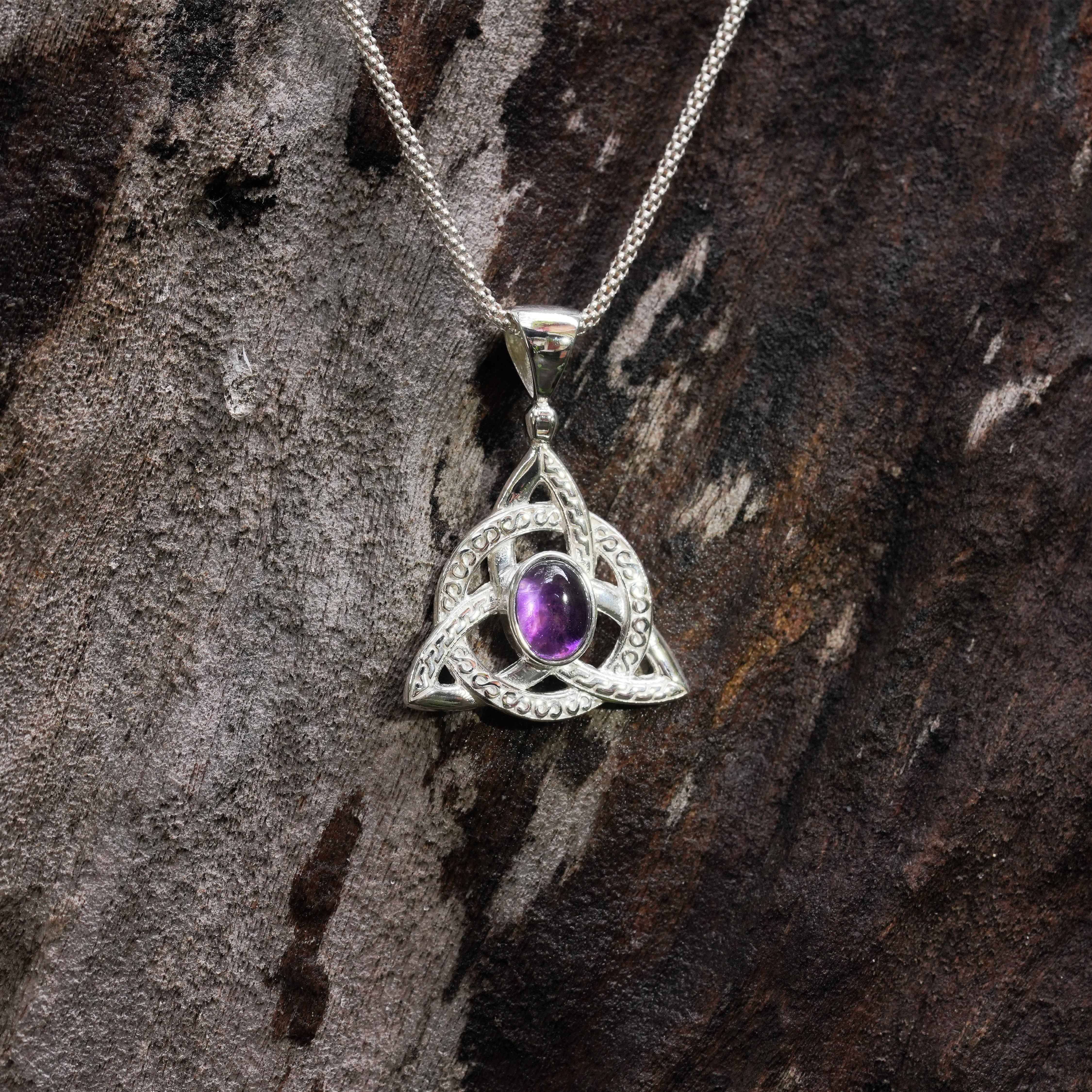 Front view of a silver triquetra pendant necklace with an oval purple Amethyst center stone. 