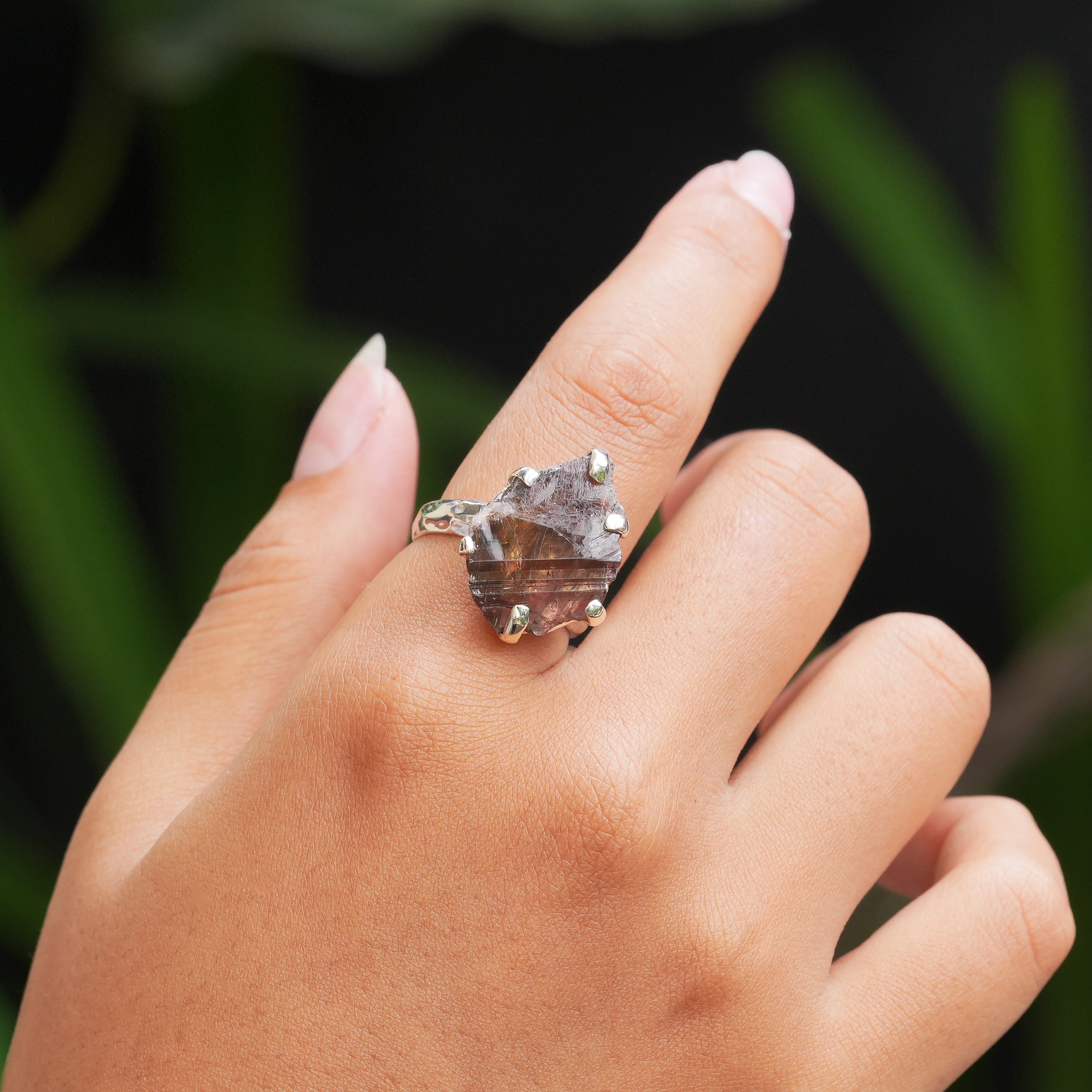Axinite prong‑set ring worn on a finger for scale