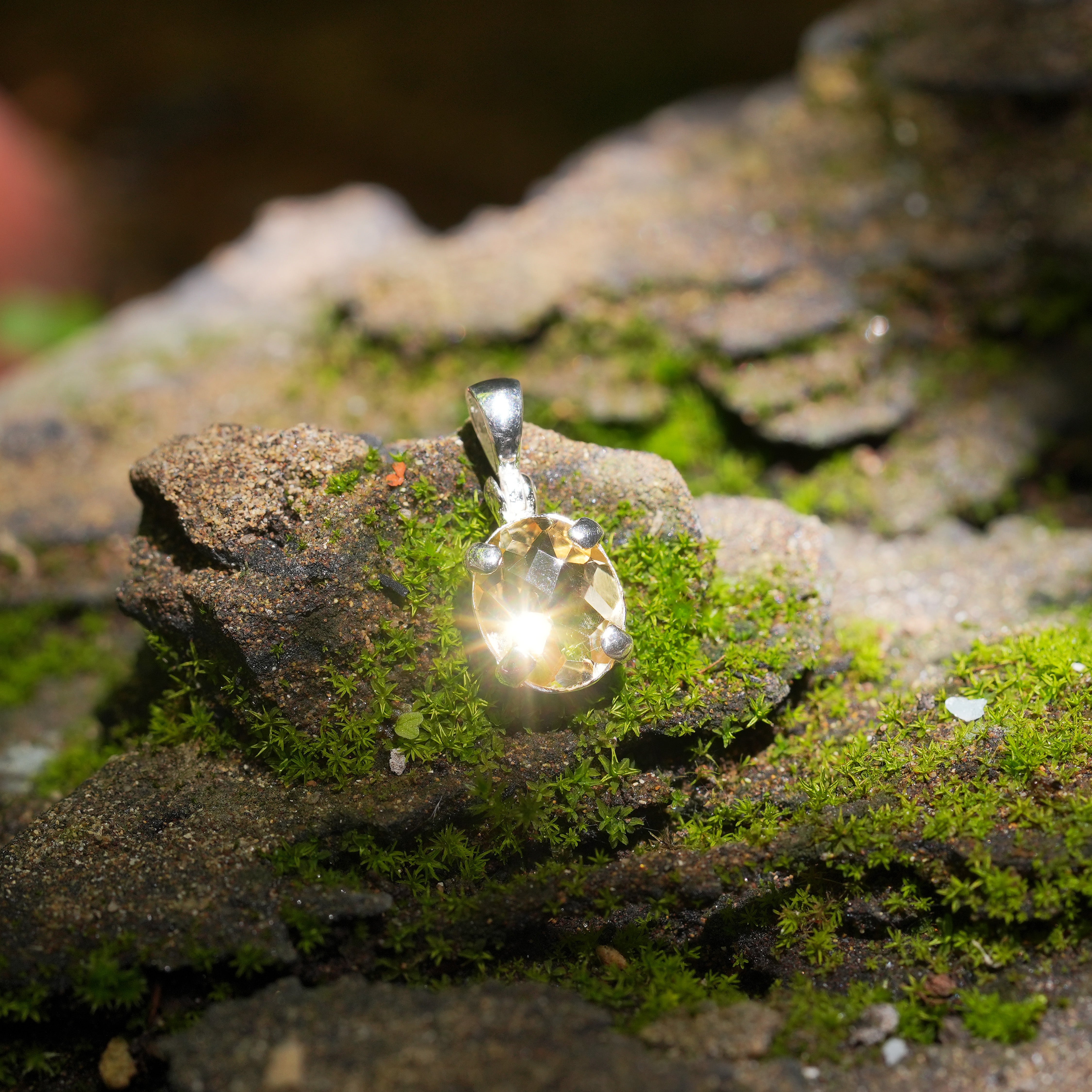 Front view of the same oval faceted citrine sterling silver pendant shown resting upright, highlighting the prong setting and gemstone facets.