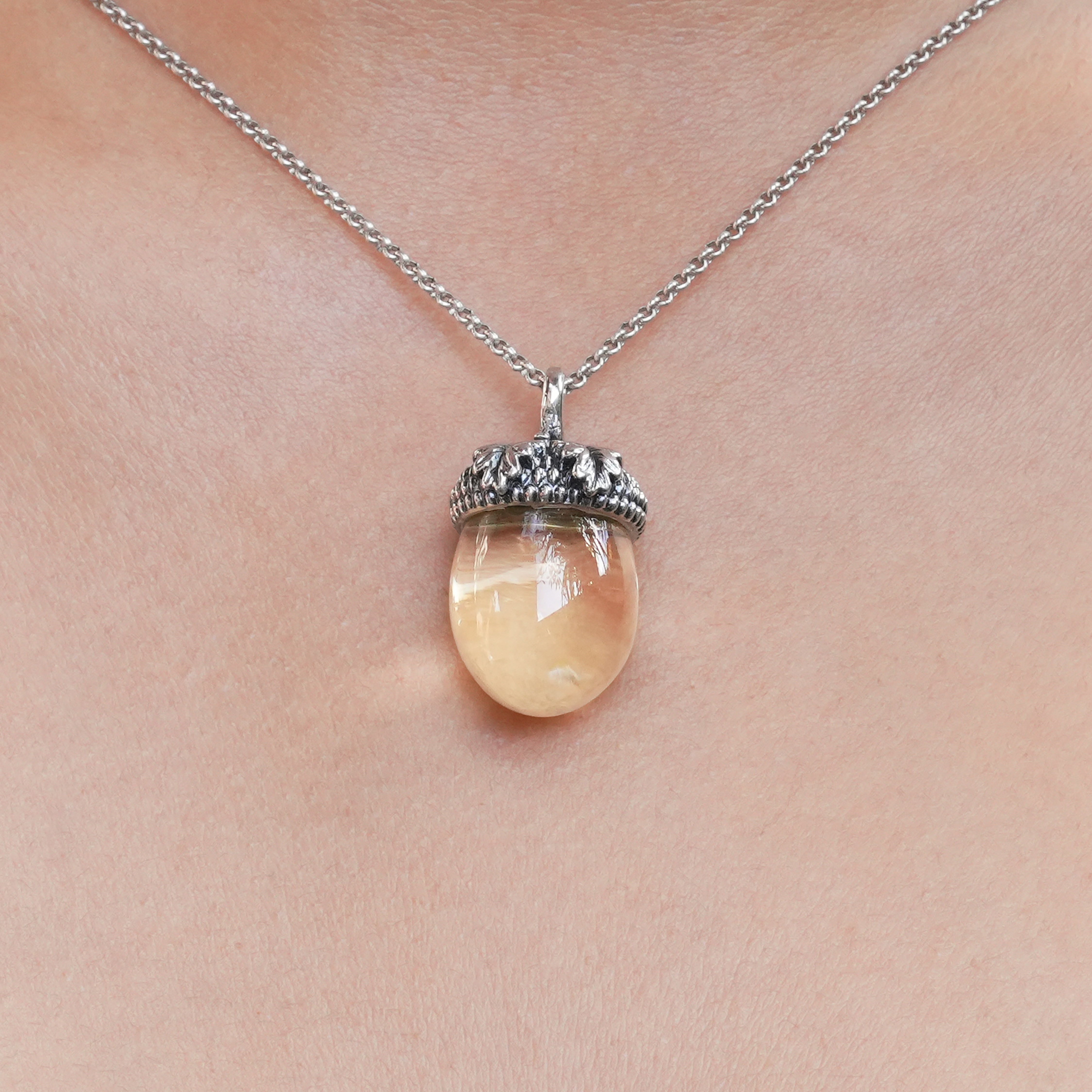 Image showing the citrine acorn pendant worn on a necklace at the center of the chest, illustrating scale and how the pendant hangs when worn.