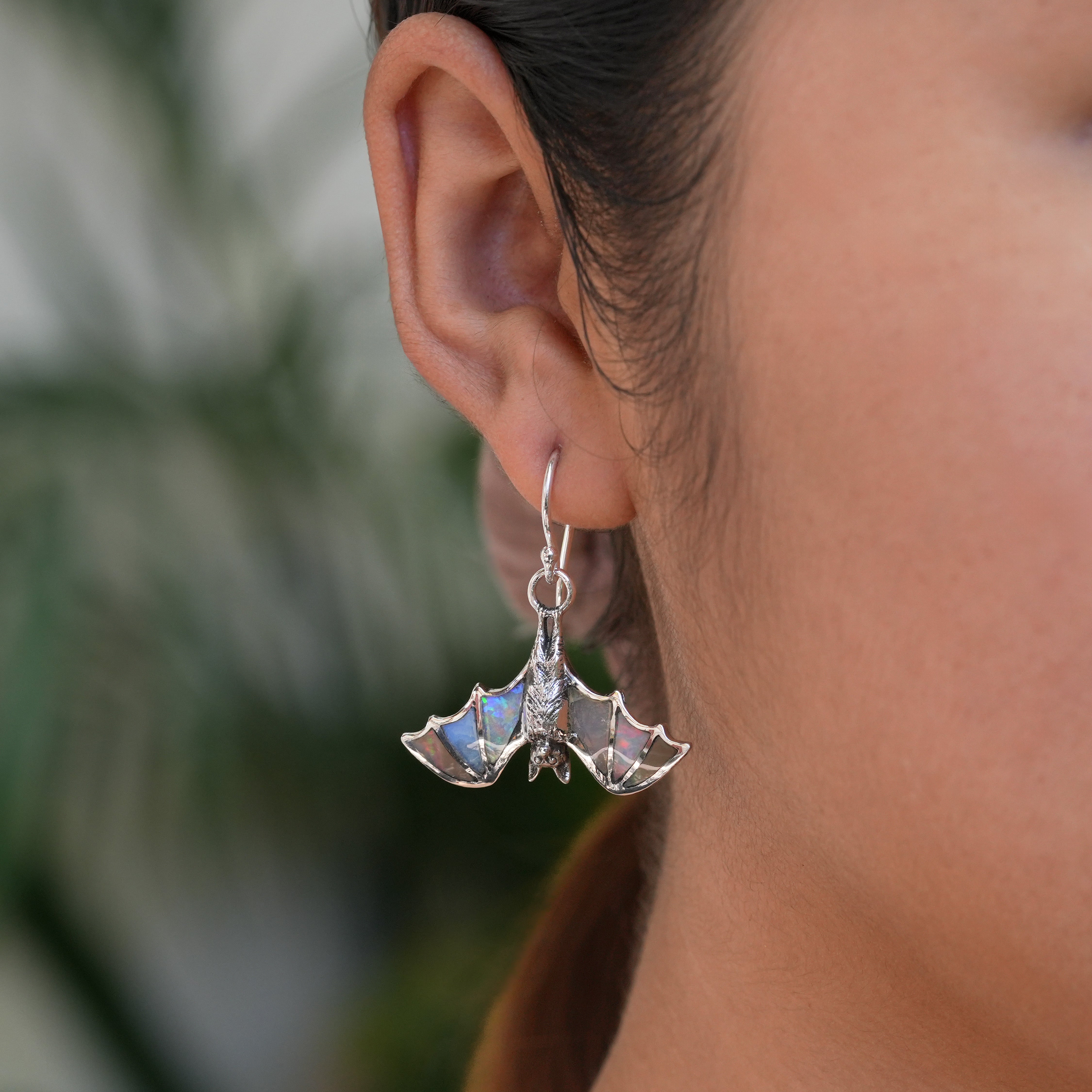 Ethiopian Opal hanging bat dangle earring worn on ear for size reference.