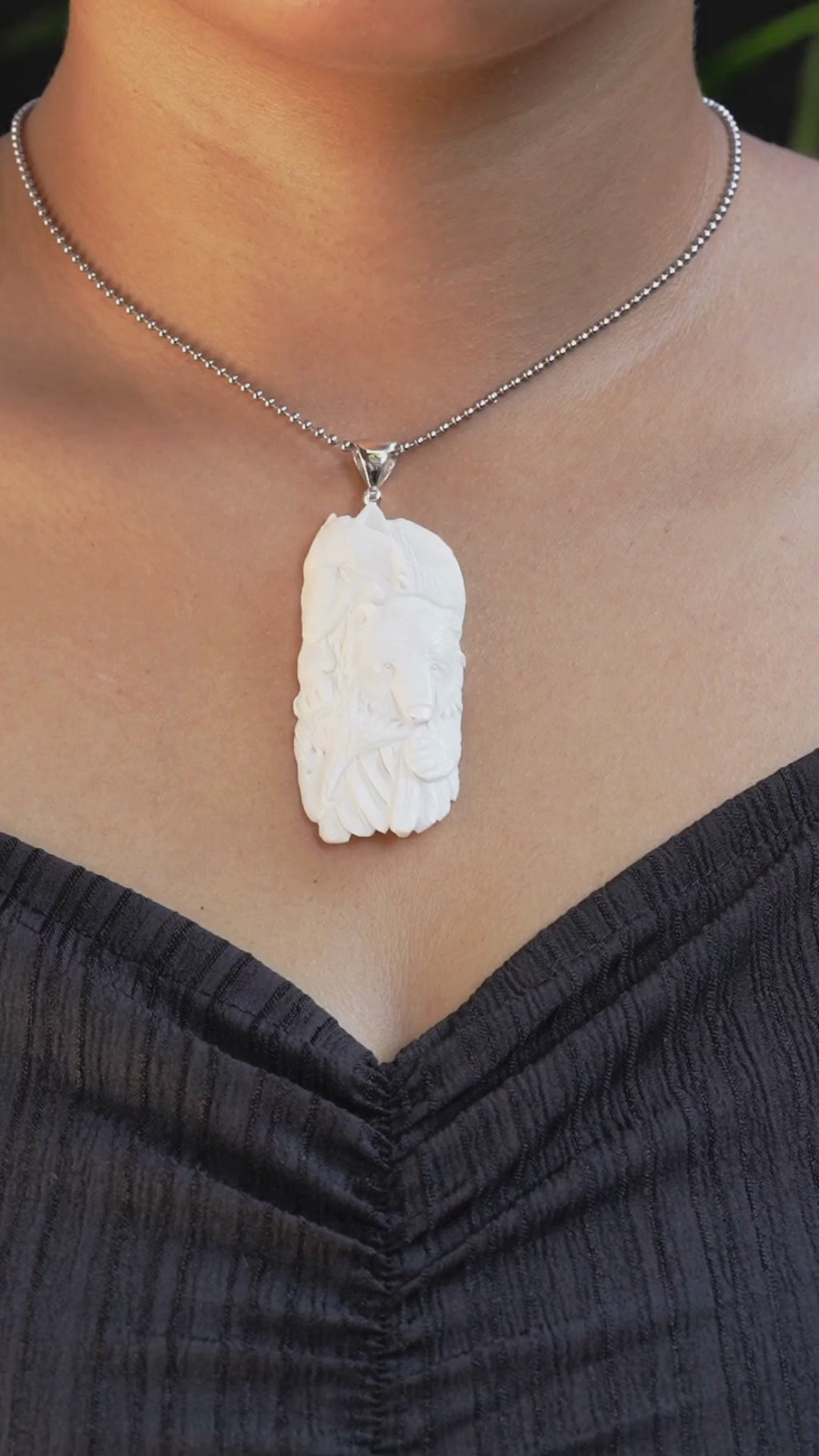 Video showing the carved buffalo bone eagle, bear, and wolf pendant worn on a chain by a model, with movement allowing the carving details, thickness, and silver bail to be viewed from multiple angles.
